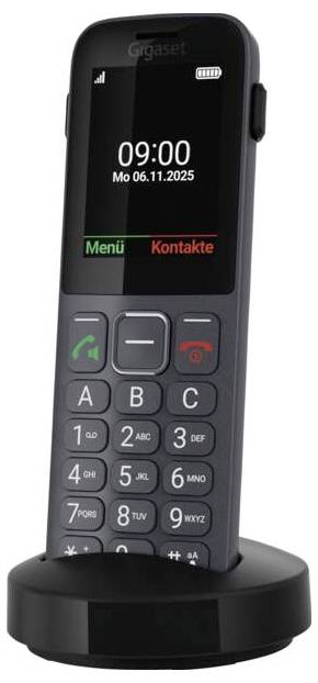 Ein schnurloses Telefon mit Tastatur und digitalem Display, das '09:00 Mo 06.11.2025' anzeigt. Es ist auf einer Ladestation montiert.