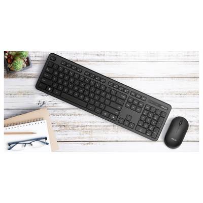 Eine schwarze Tastatur und eine schwarze Maus, die auf einem weißen Holztisch platziert sind, neben einem Notizbuch, einem Stift, einer Brille und kleinen Pflanzen.