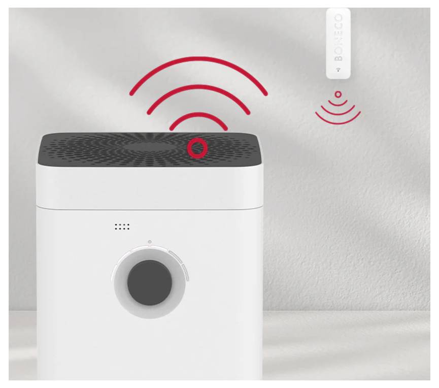 Ein weißer Luftreiniger mit einem schwarzen Deckel zeigt rote drahtlose Signalwellen, die zu einem kleinen, weiß an der Wand montierten Sensor mit der Aufschrift "BONECO" verbunden sind.