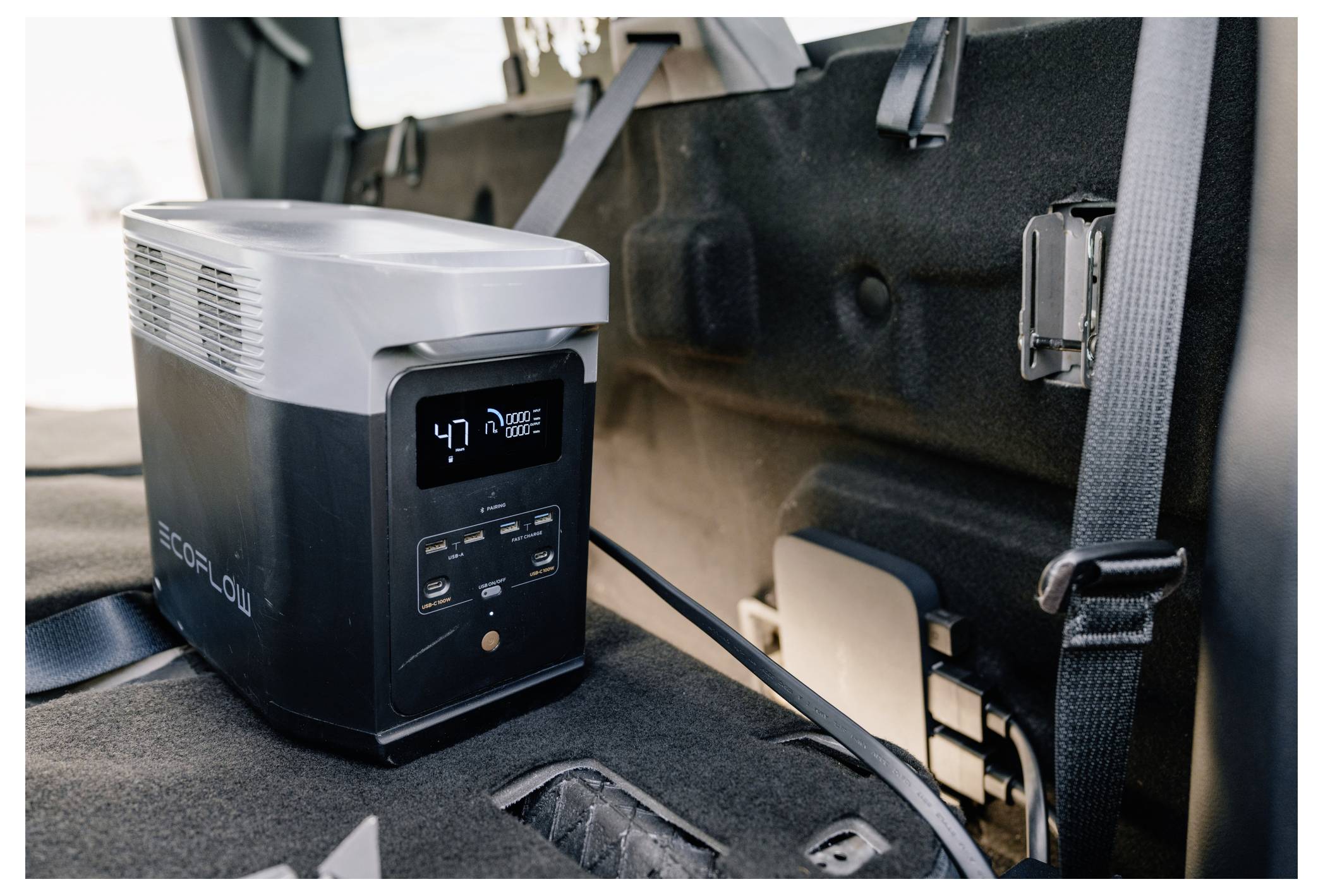 Eine mobile Stromversorgungseinheit mit einer digitalen Anzeige, die '47%' zeigt, ist sicher im Fahrzeug befestigt und einsatzbereit.