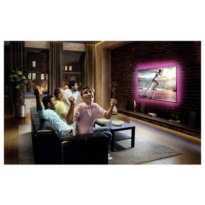 Eine Gruppe von Freunden jubelt begeistert, während sie ein Sportereignis auf einem großen Bildschirm-Fernseher in einer gemütlichen Wohnzimmeratmosphäre verfolgen.