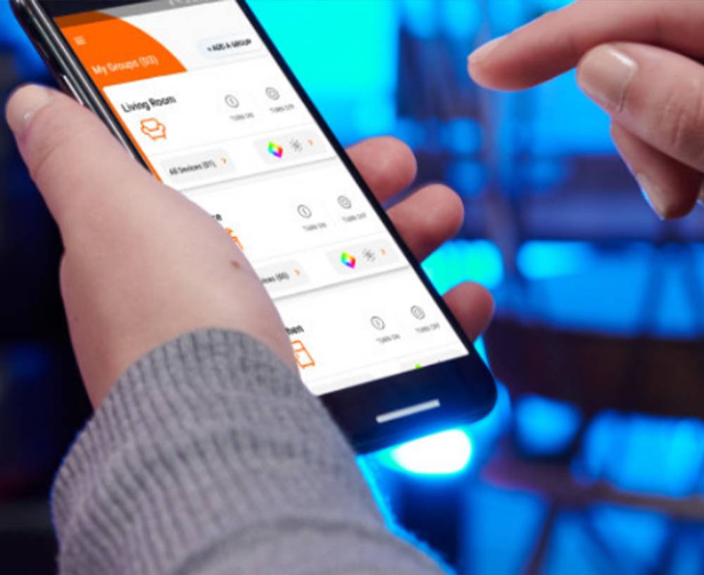 Person steuert Smart-Home-Geräte mit einer Smartphone-App, Nahaufnahme. Bildschirm zeigt Optionen für Beleuchtungs- und Temperatureinstellungen.