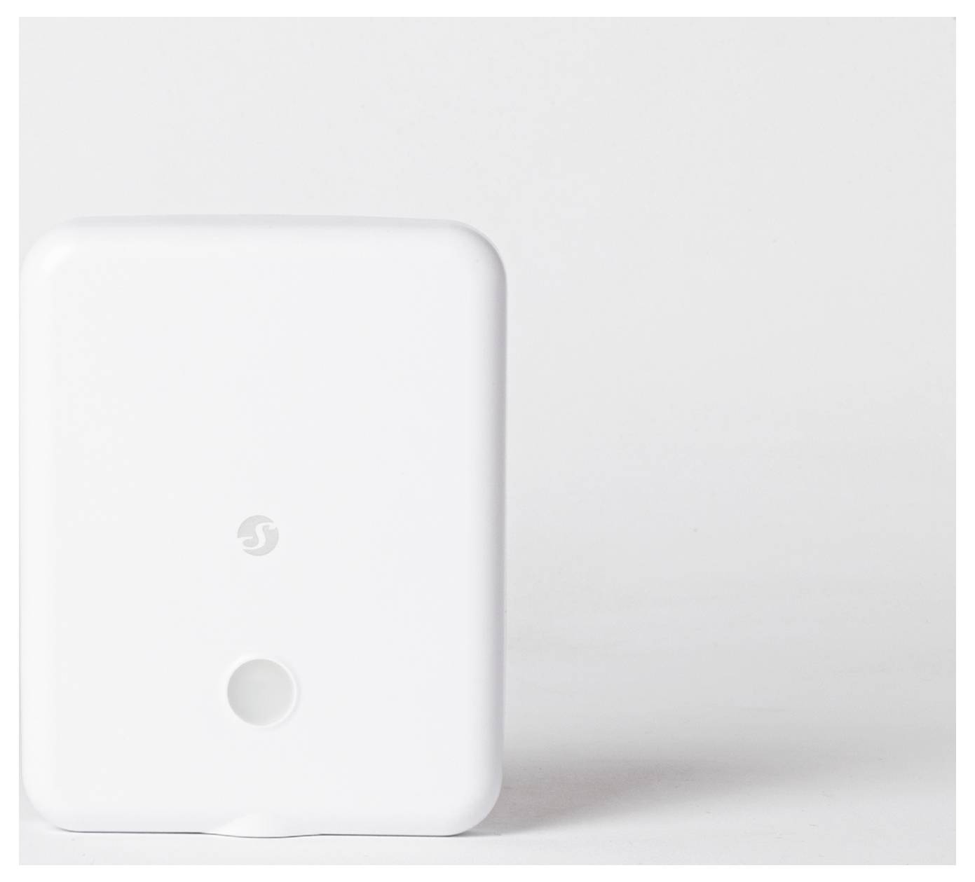 'Weißes rechteckiges elektronisches Gerät mit einem kleinen Logo und einer kreisförmigen Öffnung auf der Vorderseite, gegen einen einfarbigen Hintergrund gelehnt.'