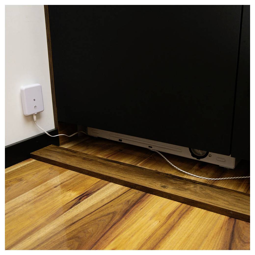 Kabelverwaltungssystem unter einem Schrank, mit sauber angeordneten Kabeln, die in ein an der Wand montiertes Gerät führen, auf einem Holzboden.