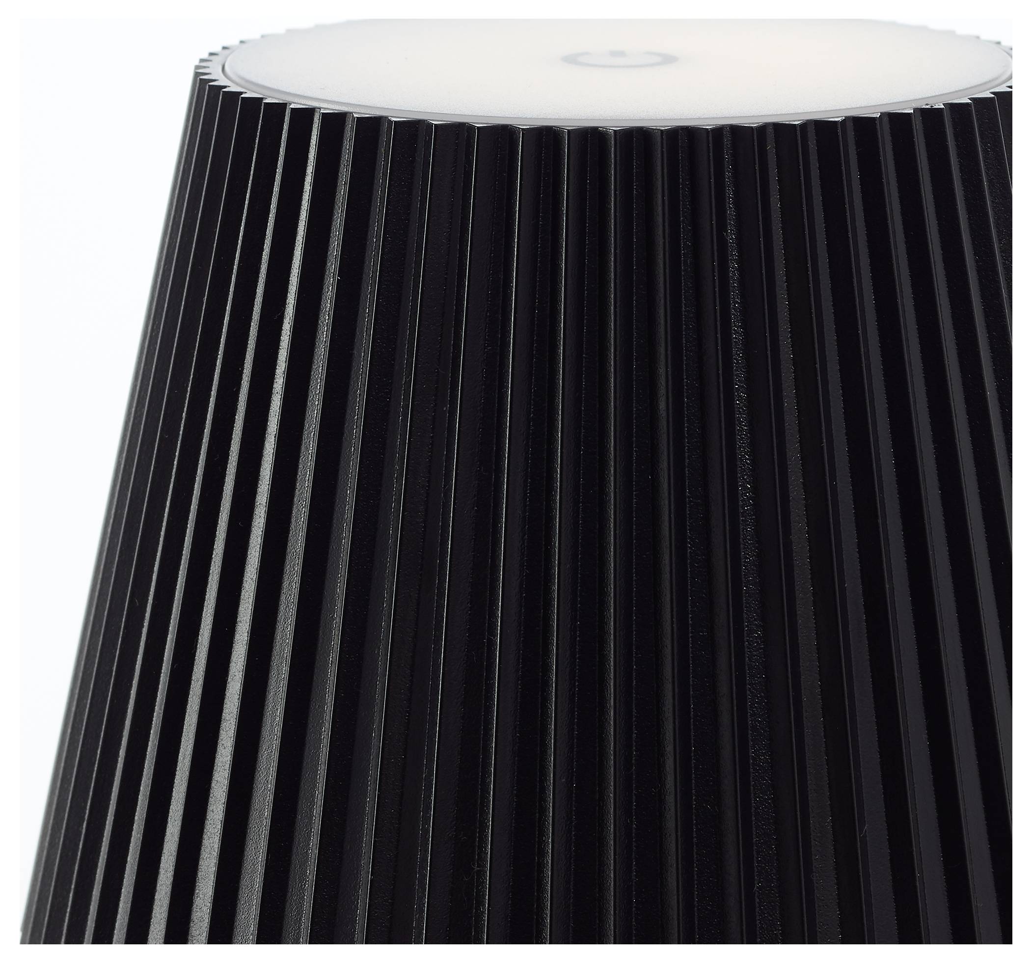 Eine Nahaufnahme einer Lampe mit einem vertikal gerippten schwarzen Schirm und einem weißen Diffusor oben.