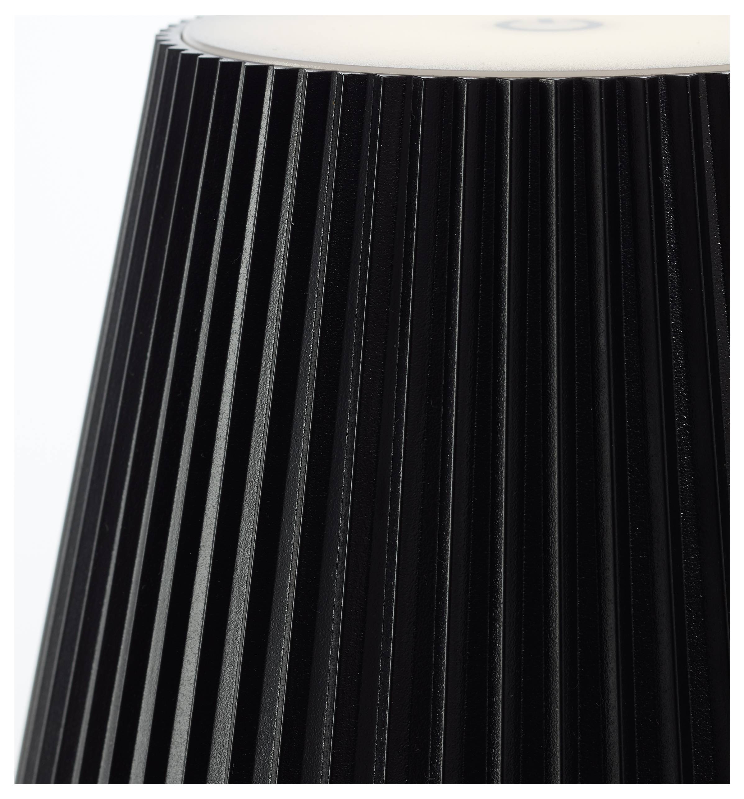 Schwarze Lampe mit vertikalen Rillen, von der Seite betrachtet, von oben beleuchtet.