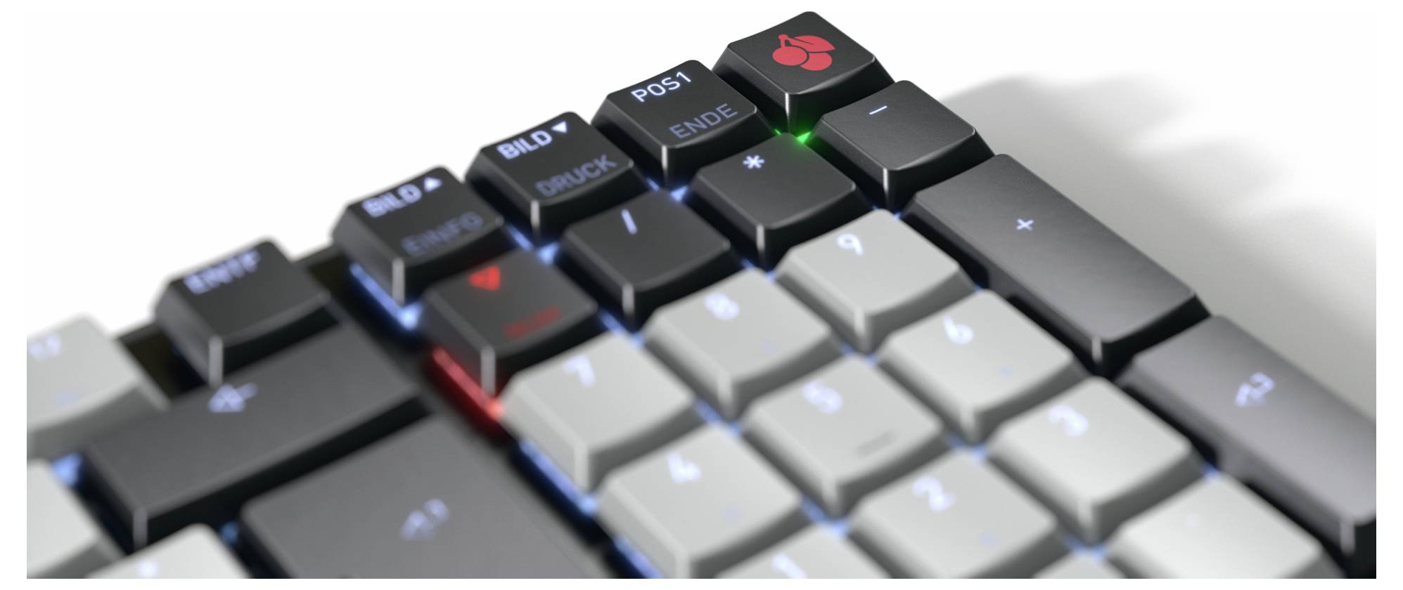 Nahaufnahme einer mechanischen Tastatur mit grauen und schwarzen Tasten, hervorgehoben durch ein rotes und ein grünes Anzeigelicht auf den Tasten oben rechts.