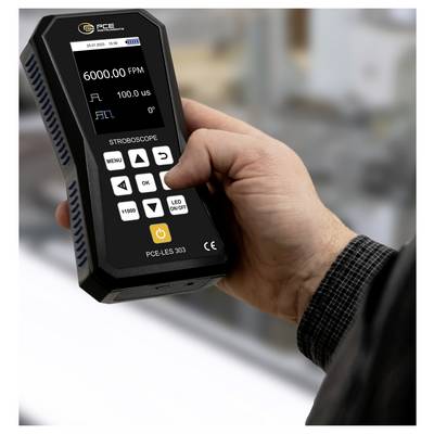Hand, die ein Stroboskop-Messgerät hält, das auf seinem Display 6000.00 FPM und 100.0 µs anzeigt.