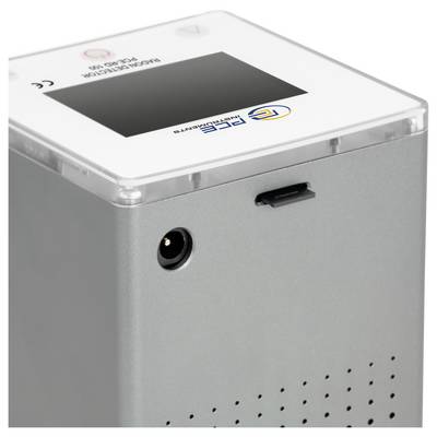 Nahaufnahme eines grauen elektronischen Gerätegehäuses mit durchsichtiger Abdeckung, Stromanschluss, Seitenschlitz und kleinen Lüftungslöchern.