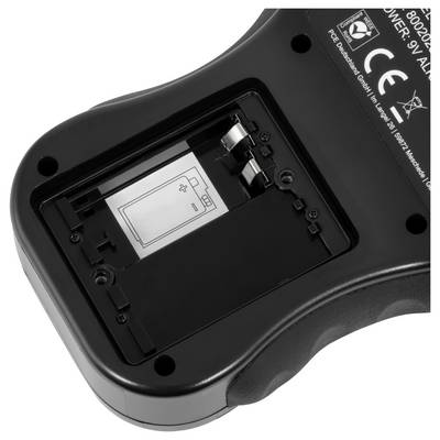 Nahaufnahme eines offenen Batteriefachs eines Geräts, das den Batterieschacht, die Metallkontakte und ein Polaritätsdiagramm zeigt.