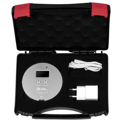 Offene schwarze Schachtel mit einem runden silbernen UV-Energiemessgerät, aufgewickeltem weißem USB-Kabel und weißem Netzteil mit roten Verschlüssen.
