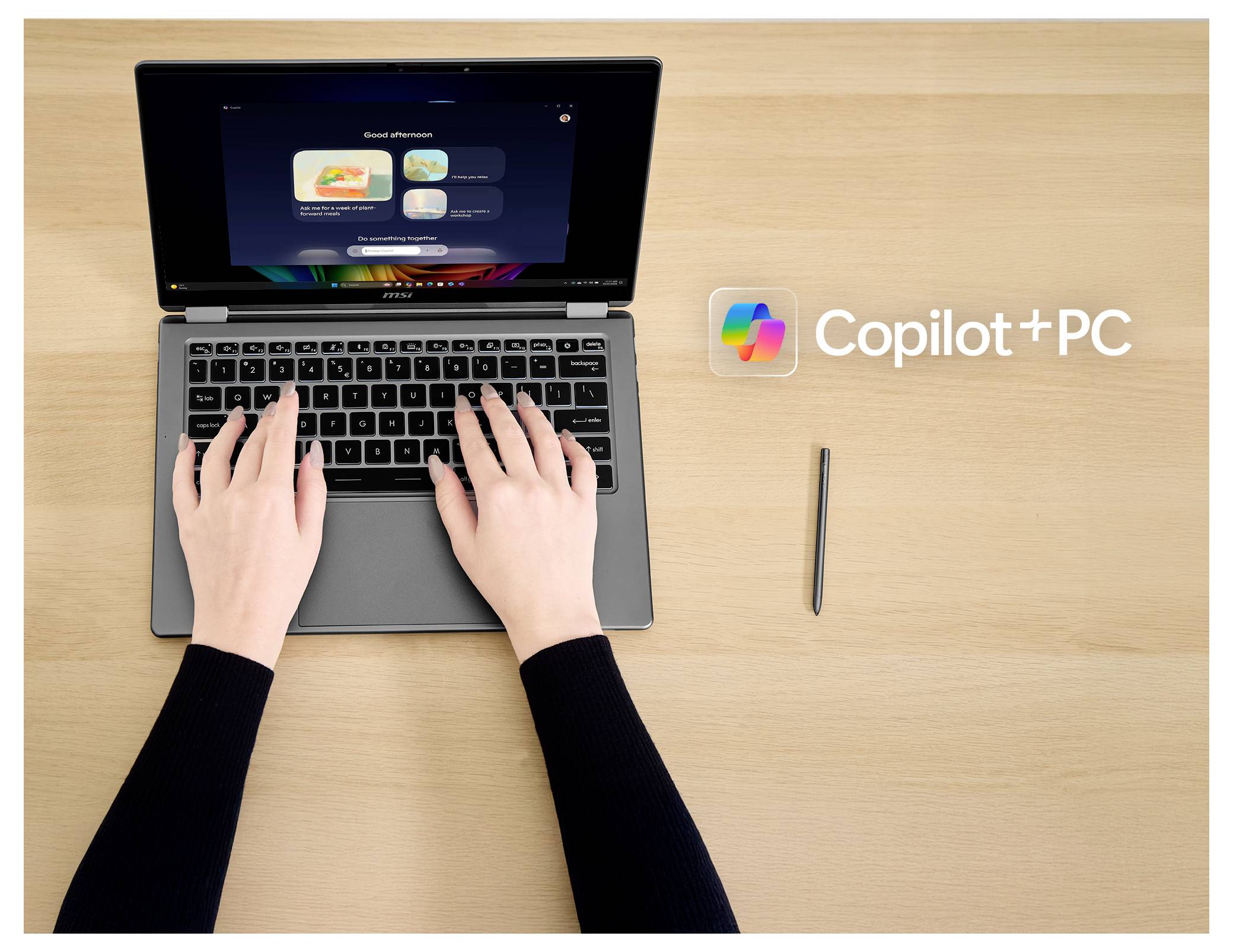 'Copilot+PC' Text neben einem offenen Laptop mit einer Person, die tippt; ein Stift in der Nähe deutet auf Touch-Funktionen hin.