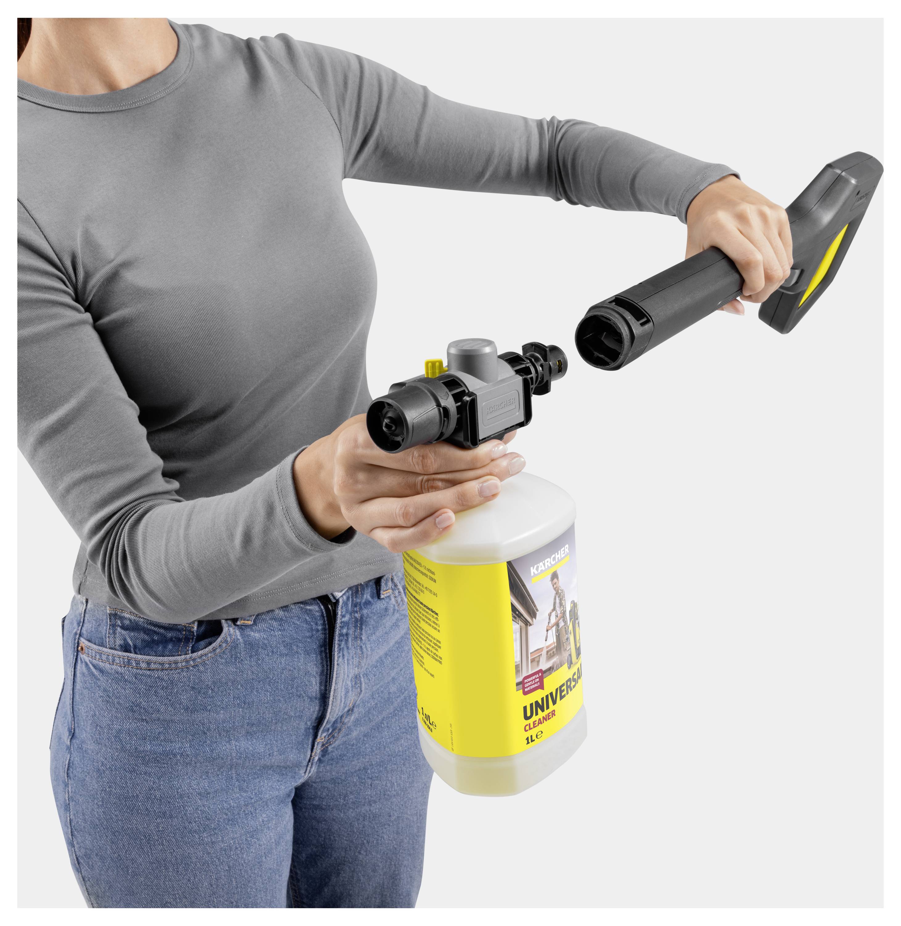 Eine Person montiert einen Hochdruckreiniger und befestigt eine Sprühdüse an einer gelben Waschmittelflasche mit der Aufschrift „Universal Cleaner".