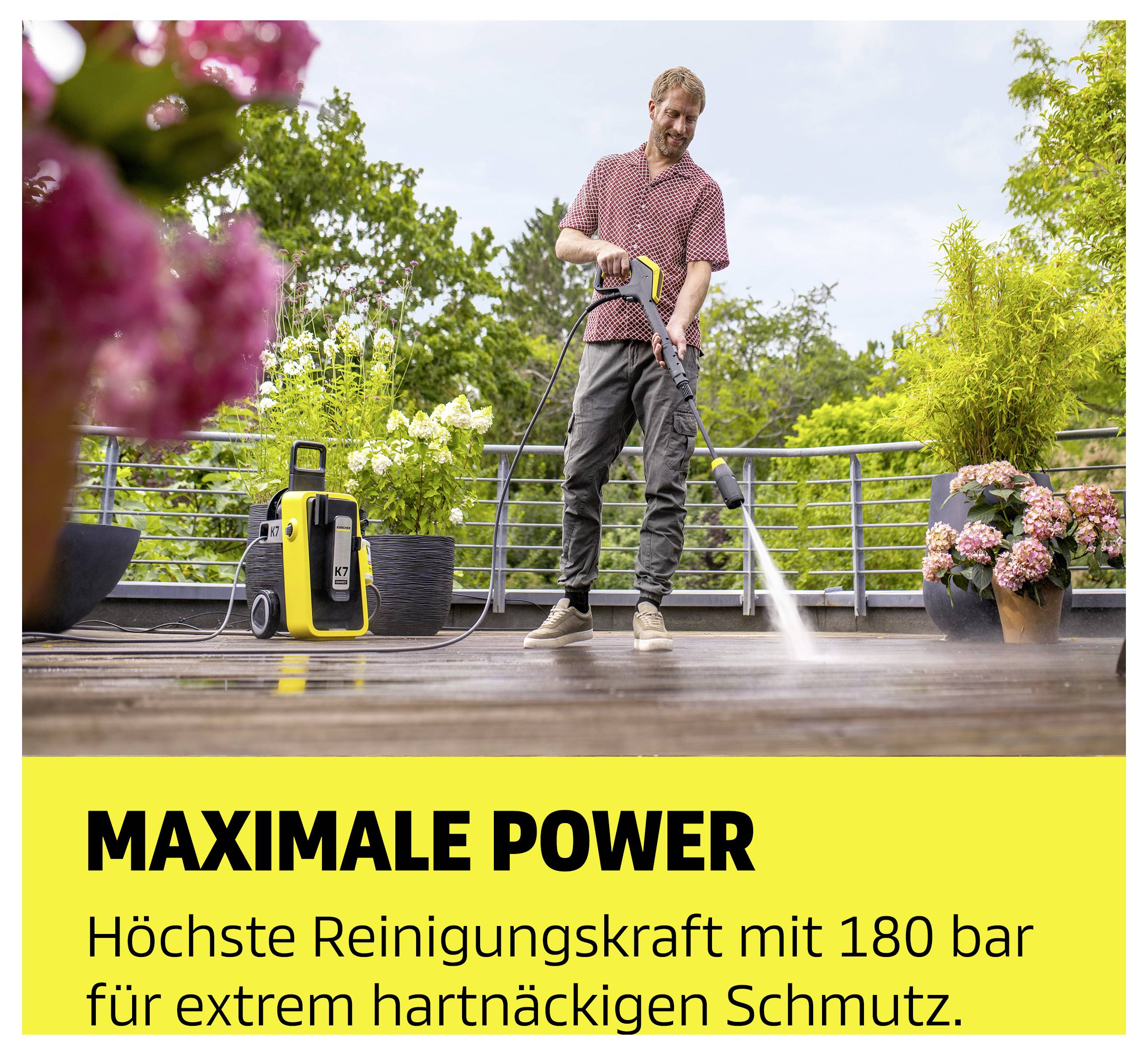 Mann reinigt Terrasse mit Hochdruckreiniger; Werbetext: 'MAXIMALE POWER' und 'Höchste Reinigungskraft mit 180 bar für extrem hartnäckigen Schmutz.'<br>