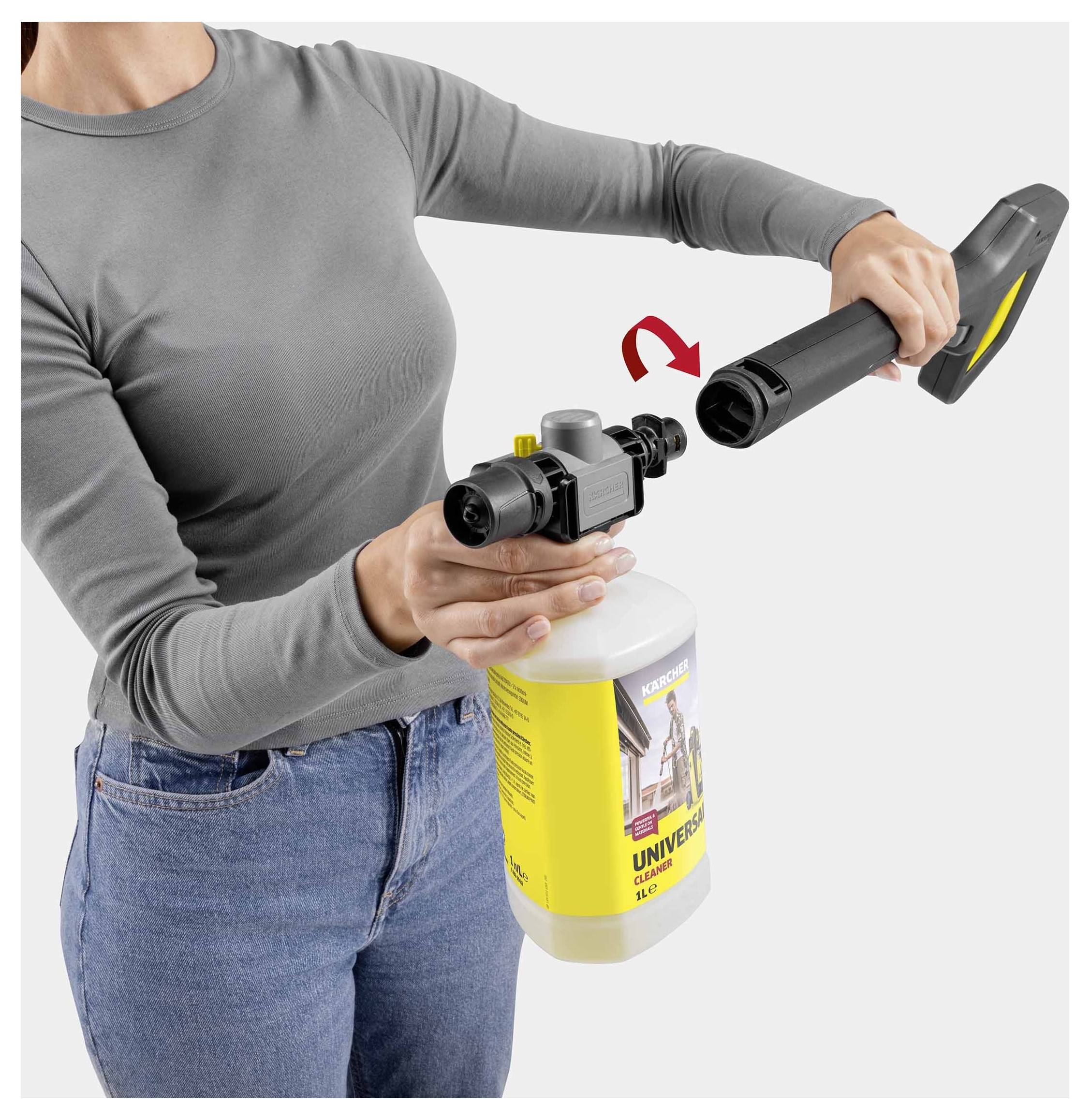 Person, die eine Sprühflasche an einem Hochdruckreiniger befestigt, während die Montage demonstriert wird. Die Flasche ist mit 'Universalreiniger' beschriftet.