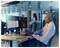 Eine Person in einem Videoanruf mit mehreren Teilnehmern, die auf einem Computermonitor angezeigt werden, während Tabellenkalkulationsdaten auf einem anderen Bildschirm sichtbar sind.
