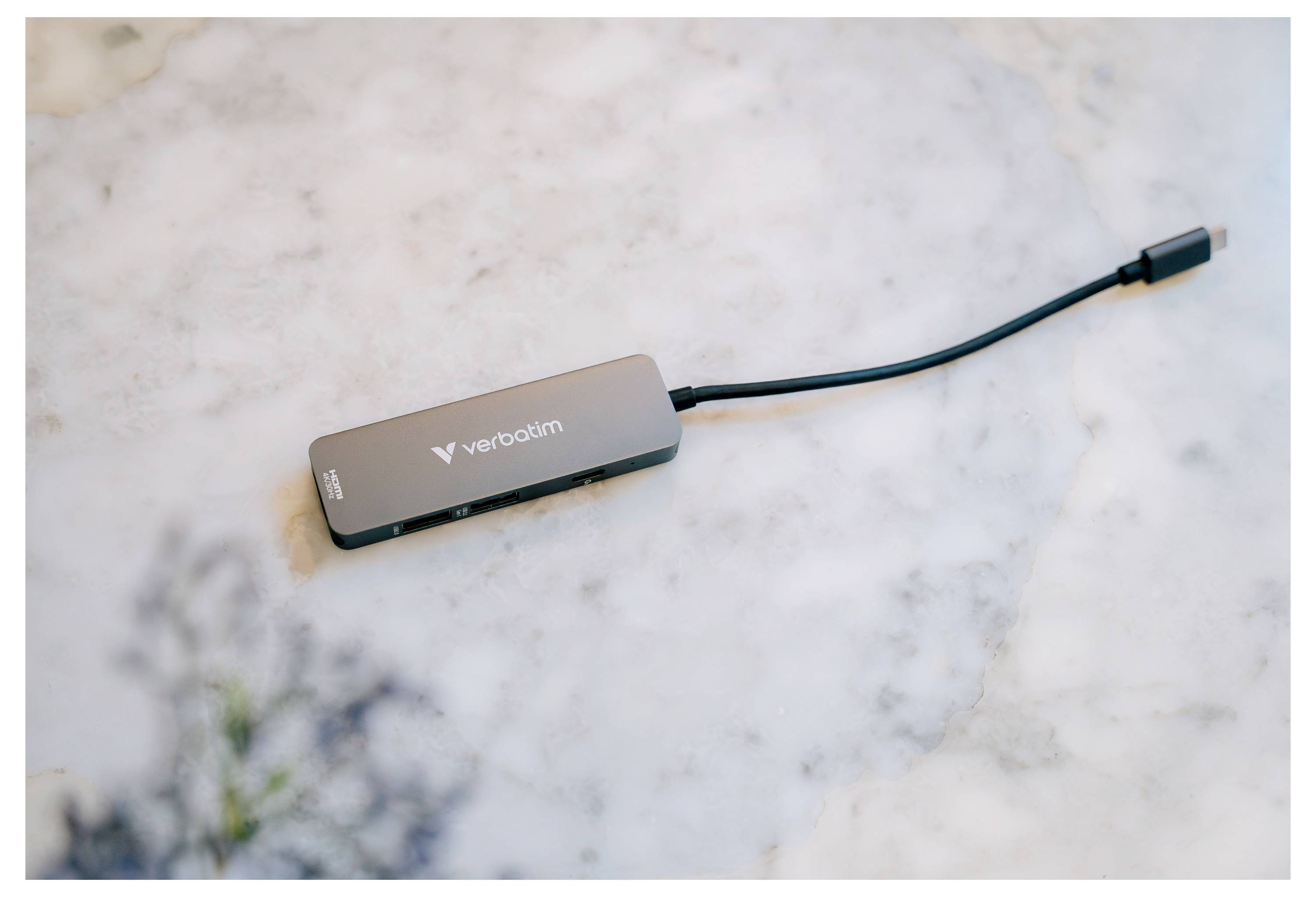 Ein kompakter Verbatim USB-C-Hub mit einem kurzen angebrachten Kabel liegt auf einer Marmoroberfläche.