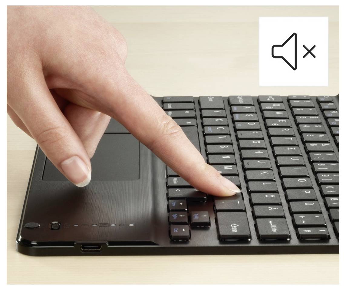 Eine Hand drückt eine Taste auf einer Laptop-Tastatur mit einem stummgeschalteten Lautsprechersymbol, das anzeigt, dass der Ton ausgeschaltet ist.