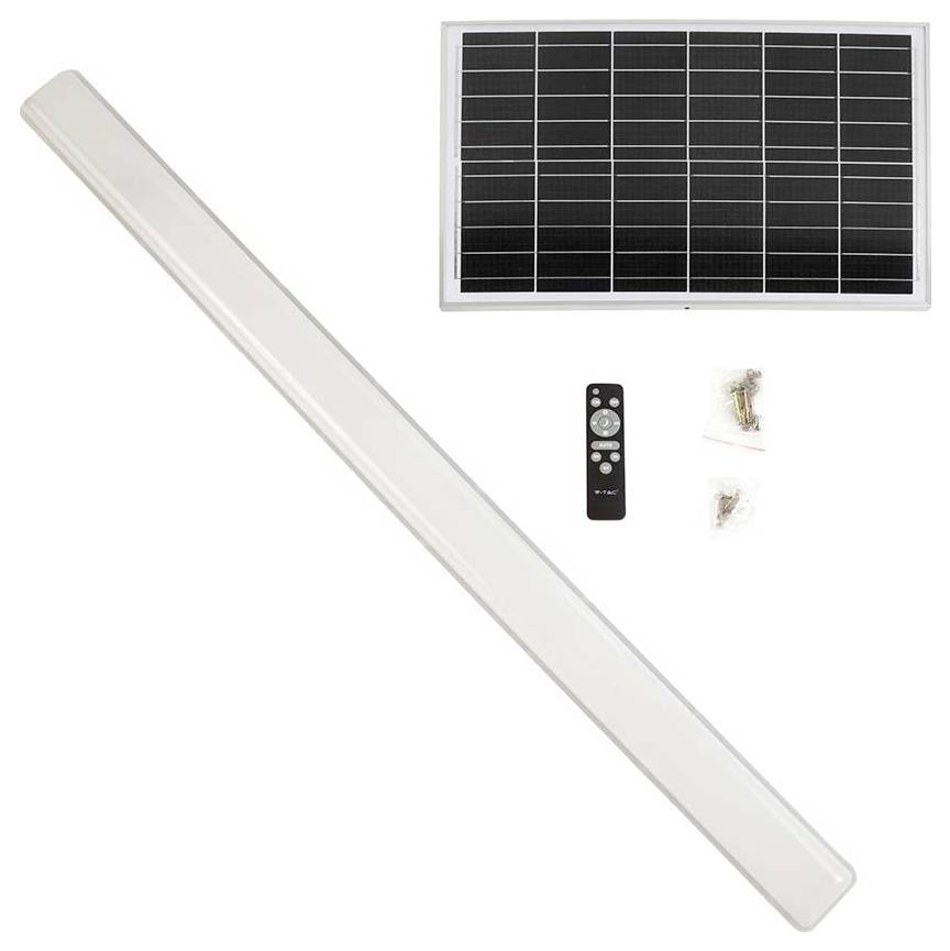 Ein Solarpanel mit einer Fernbedienung und Montagezubehör neben einer langen, rechteckigen LED-Leuchtenarmatur.