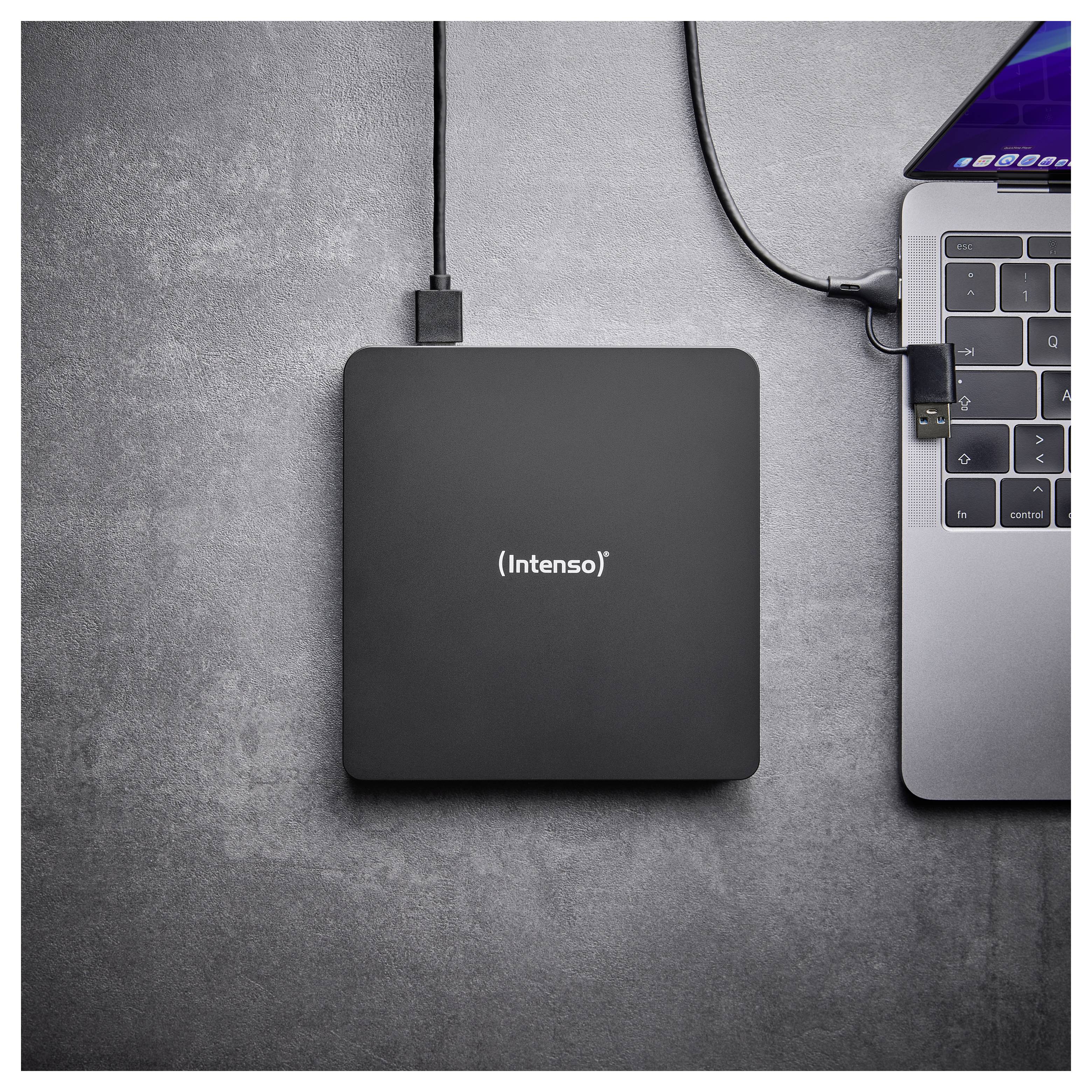 Eine externe Festplatte mit der Bezeichnung "Intenso" ist über ein USB-Kabel mit einem Laptop auf einer grauen Oberfläche verbunden.