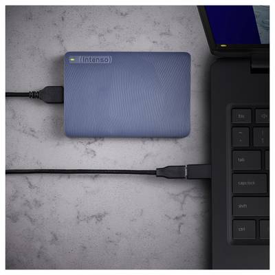 Eine externe blaue Festplatte, die über ein USB-Kabel mit einem schwarzen Laptop auf einer grauen Oberfläche verbunden ist, wobei der Laptop teilweise auf der rechten Seite sichtbar ist.
