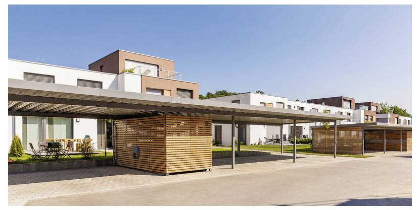 Moderne Reihe von Apartment-Häusern mit überdachten Carports und Holzlattenzäunen zur Wahrung der Privatsphäre an einem sonnigen Tag