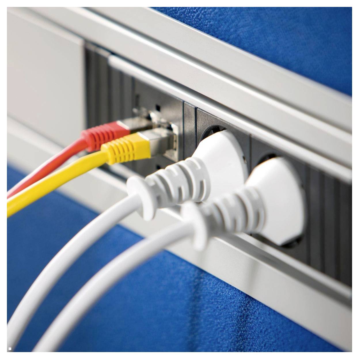 Eine Wandsteckdose mit zwei weißen Stromsteckern, einem roten Ethernet-Kabel und einem gelben Ethernet-Kabel, die daran angeschlossen sind, an einer blauen Wand.