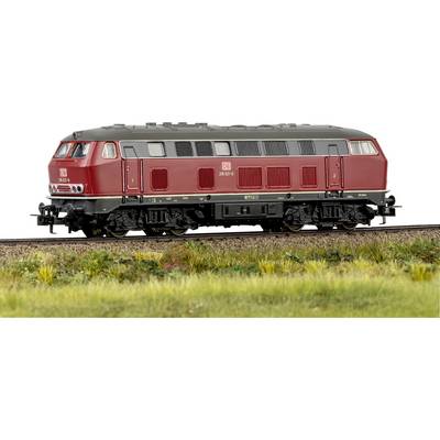 Eine rote Zuglok mit der Bezeichnung „DB 218 261-6" auf einem Gleis mit Gras und Wildblumen im Vordergrund, die eine ländliche Eisenbahnszene zeigt.