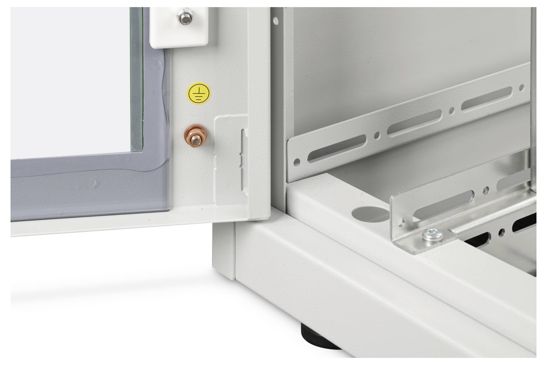 Eine Nahaufnahme eines elektrischen Gehäuses, das ein offenes Panel, ein Erdungssymbol und innere Halterungen zur Kabelführung zeigt.