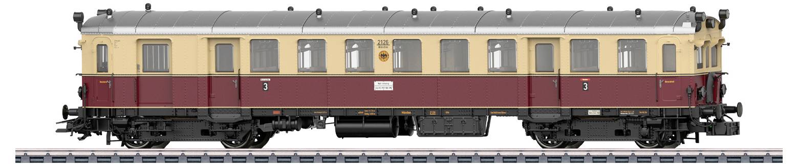 Ein Modellzug-Waggon mit beleuchteten Fenstern zeigt Miniaturfiguren, die im Inneren sitzen, einschließlich einer in Schaffneruniform, die daneben steht.