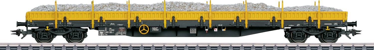 Seitenansicht eines gelb-schwarzen Zugfrachtgüterwagens, beladen mit Schotter, auf einem Eisenbahngleis positioniert.