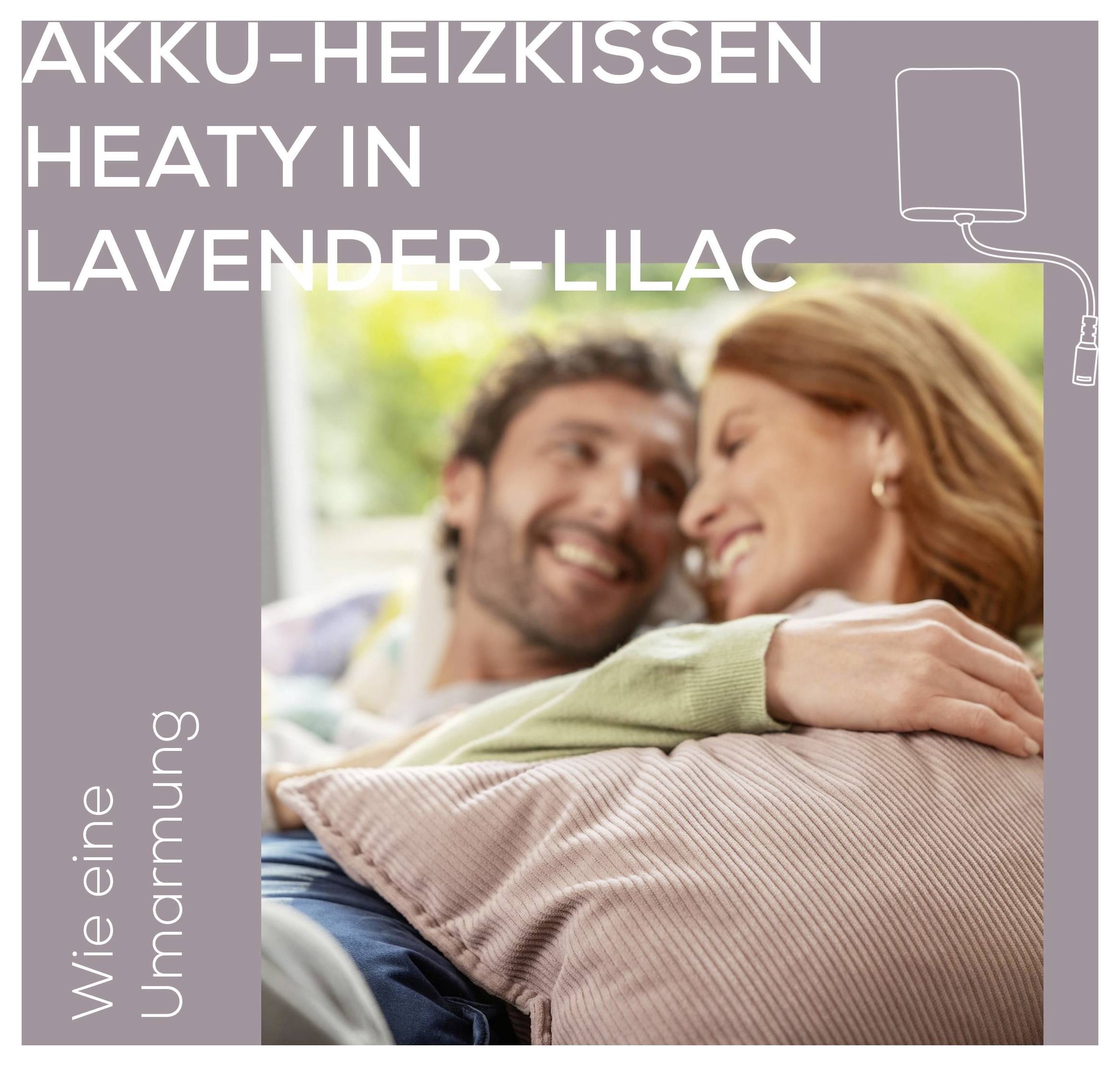 Ein Paar lächelt und entspannt sich auf einem Sofa mit einem lavendelfarbenen Wärmekissen. Text: „Heaty in Lavender-Lilac" und „Wie eine Umarmung".
