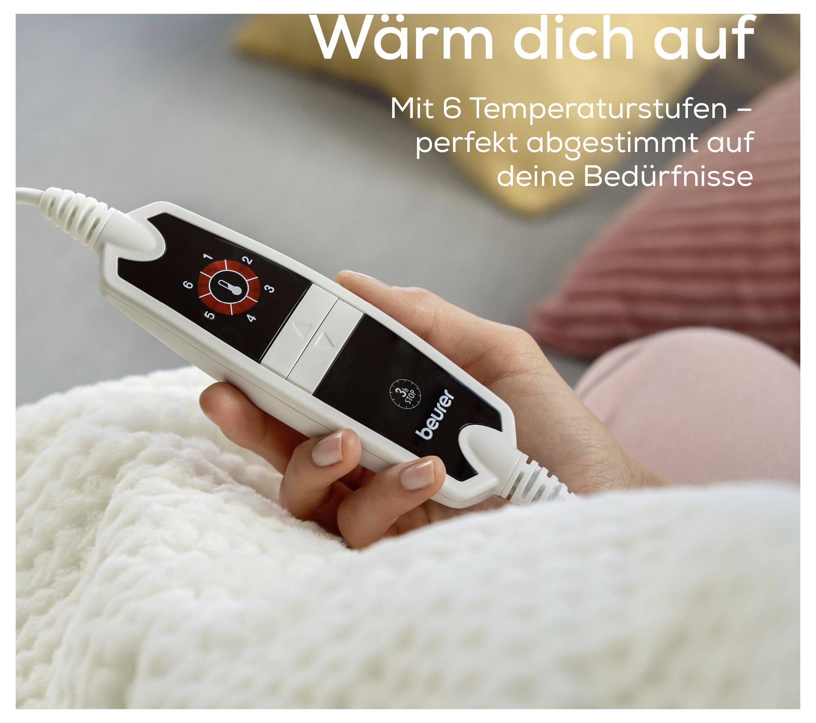 Eine Hand hält eine Wärmekissen-Fernbedienung mit Text „Wärm dich auf. Mit 6 Temperaturstufen - perfekt abgestimmt auf deine Bedürfnisse."