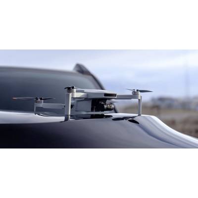 Eine kompakte Drohne ruht auf einer Motorhaube eines Autos, bereit zum Flug, und spiegelt moderne Technologie und Mobilität in einer Außenumgebung wider.