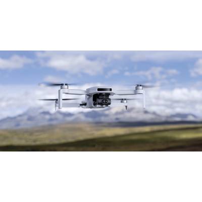 Eine Drohne fliegt am Himmel über eine unscharfe Landschaft mit Bergen im Hintergrund, was auf die Verwendung für Luftaufnahmen oder Luftvidografie hindeutet.