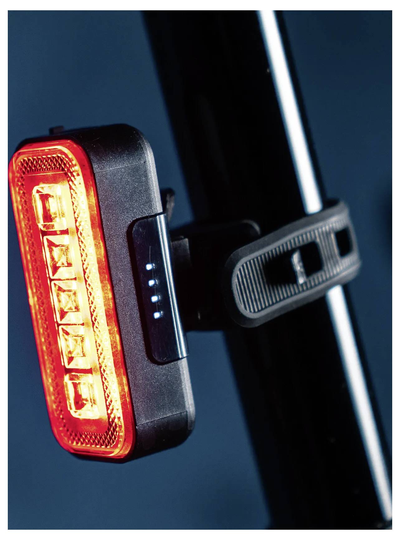 Ein rotes LED-Fahrrad-Rücklicht an einem schwarzen Sattelrohr montiert, das ein leuchtendes rotes Licht und eine Reihe von blauen Batterieanzeigerlichtern zeigt.