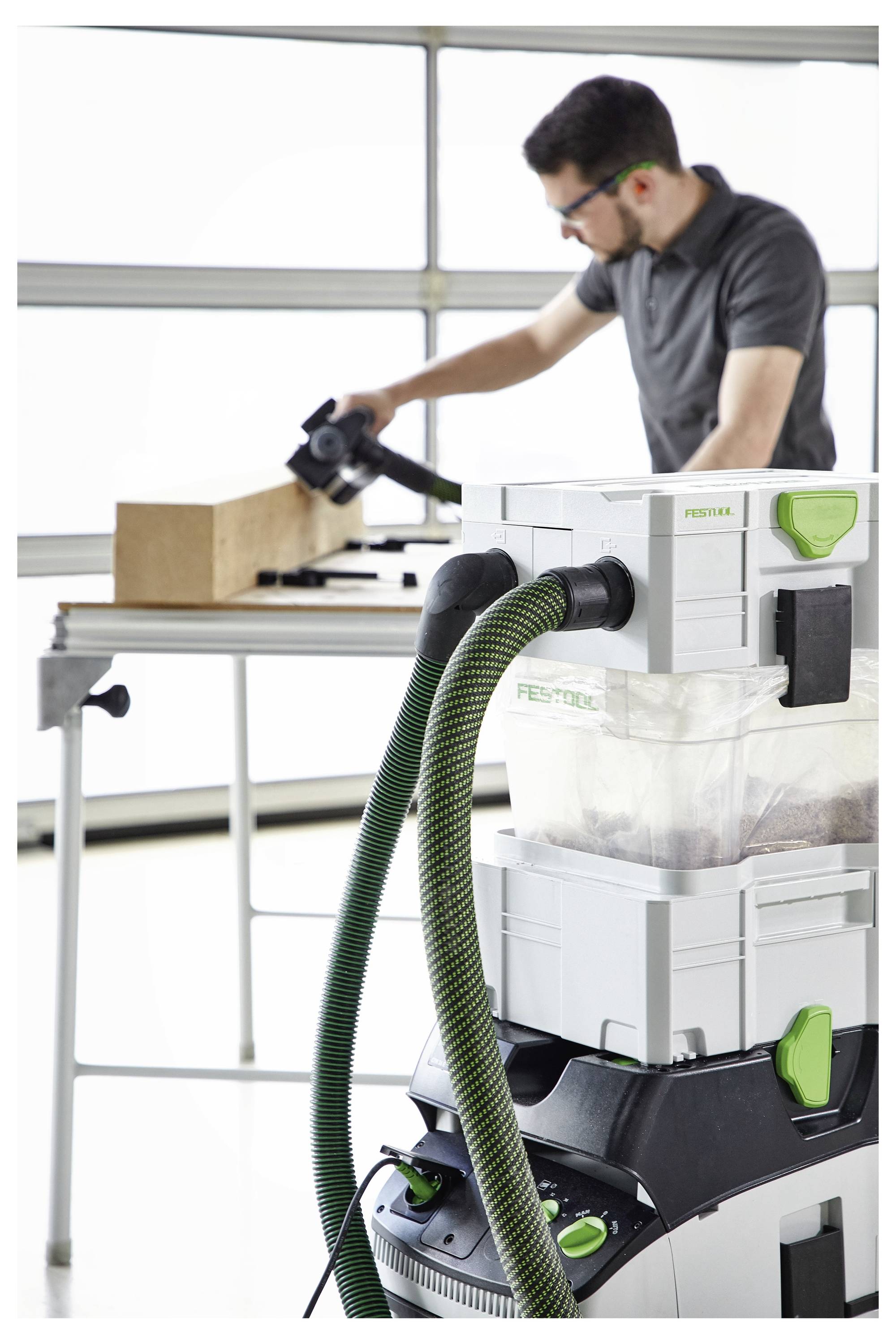 Eine tragbare Werkbank mit durchlöcherter Holzplatte, montiert auf einem Metallrahmen. Das Wort 'FESTOOL' ist auf der Basis sichtbar.