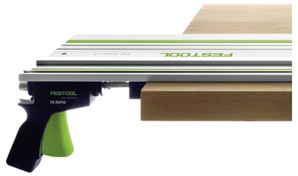 Ein Präzisions-Schneidewerkzeug von Festool mit grünem Griff wird auf einem Holzbrett eingespannt und zeigt seine Verwendung in der Zimmerei für gerade Schnitte.