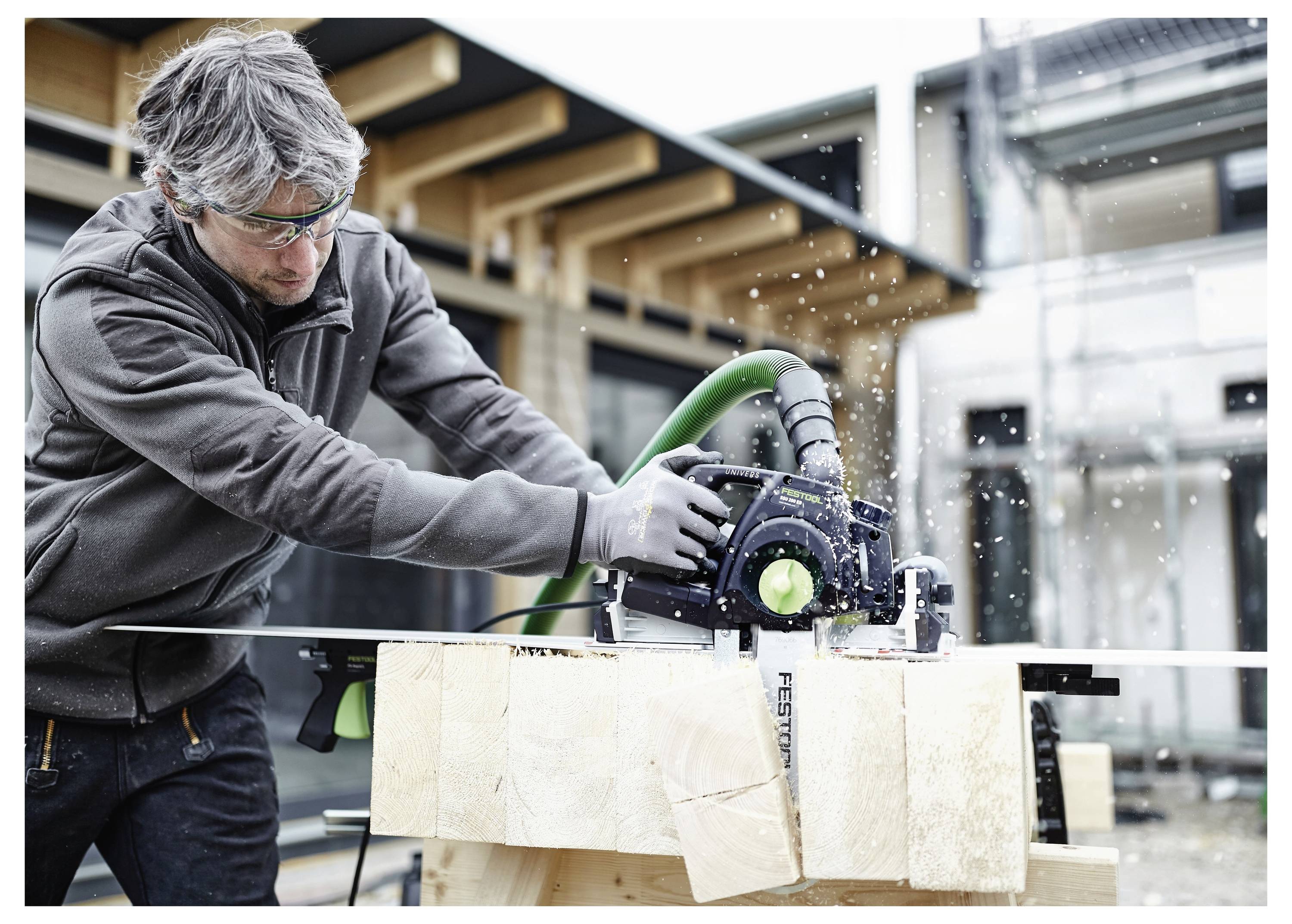 Eine Person schneidet Holz mit einer Tischkreissäge in einer gut beleuchteten Werkstatt und konzentriert sich intensiv auf die Aufgabe für Präzision.