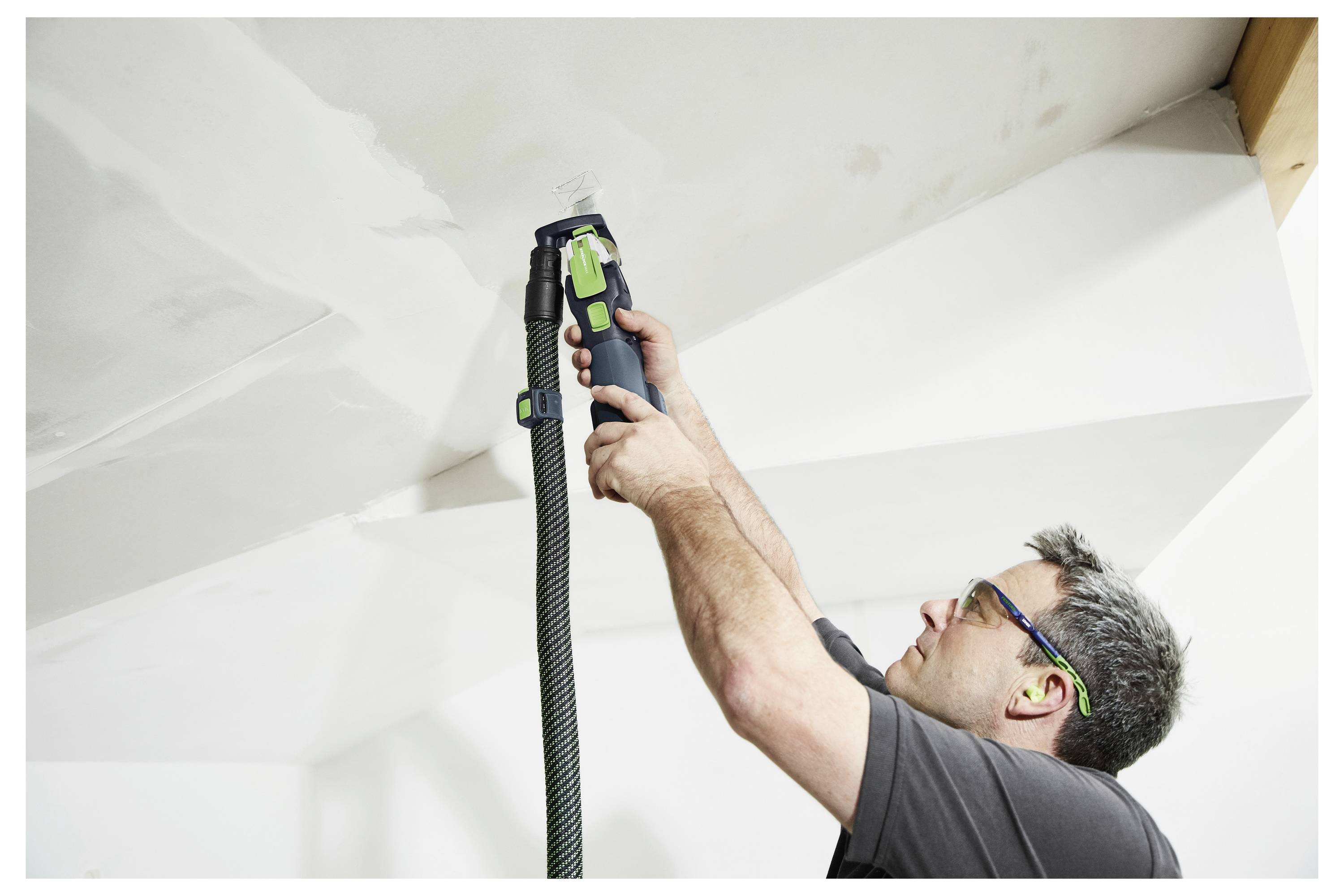 Eine grüne und schwarze Festool HKC 55 EB Handkreissäge mit Staubsackaufsatz, entwickelt zum präzisen und effizienten Schneiden von Holz.