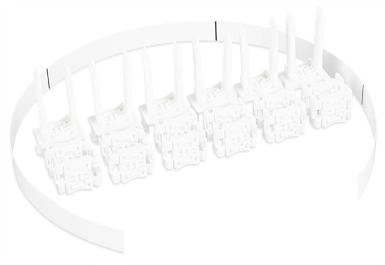 Eine Reihe weißer Kunststoff-Elektronikstecker, die an einem gebogenen weißen Streifen befestigt sind und auf einer weißen Oberfläche positioniert sind.