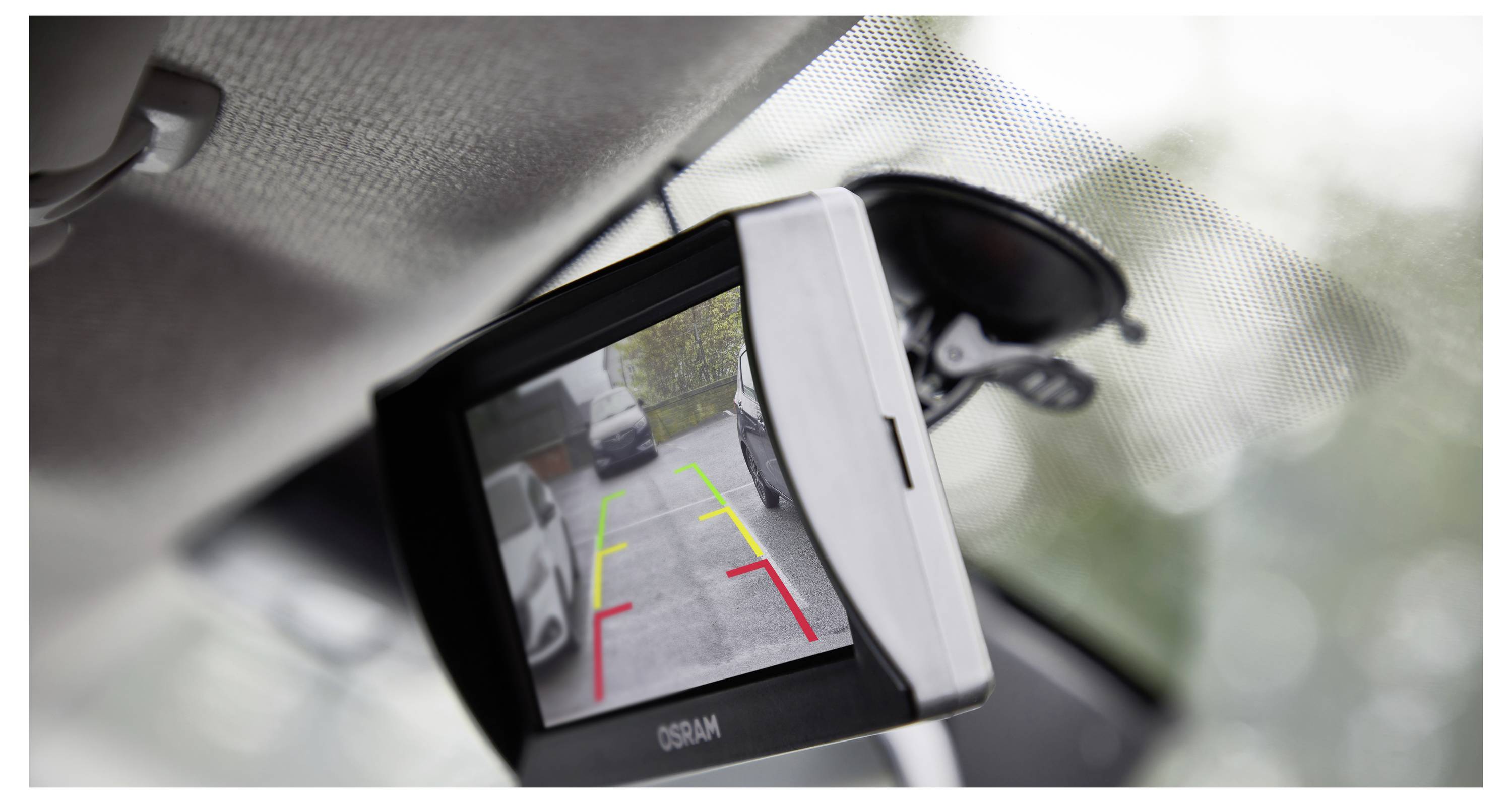 Ein Rückfahrtspiegel-Display eines Autos mit der Ansicht einer Rückfahrkamera und Parkrichtlinien in Grün, Gelb und Rot neben geparkten Autos.