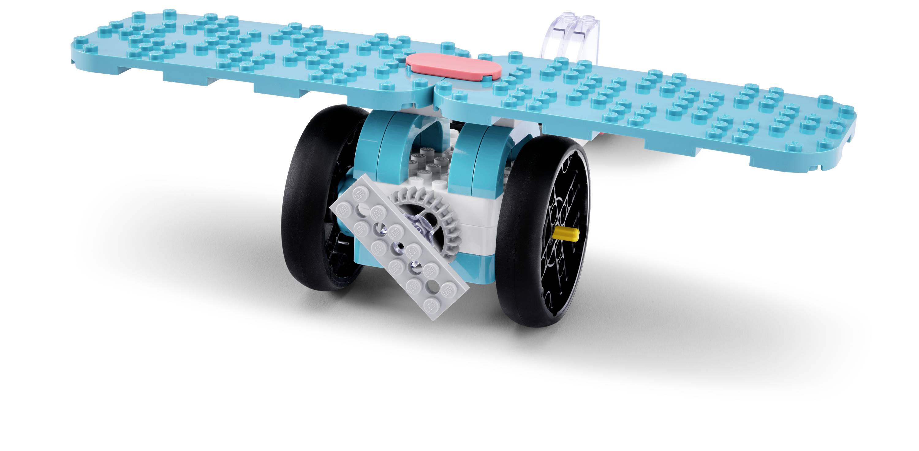 Ein kleines Spielzeugflugzeug aus türkisen und schwarzen Kunststoffbausteinen mit zwei Rädern und einem flachen Flügel mit einem roten Baustein oben drauf.