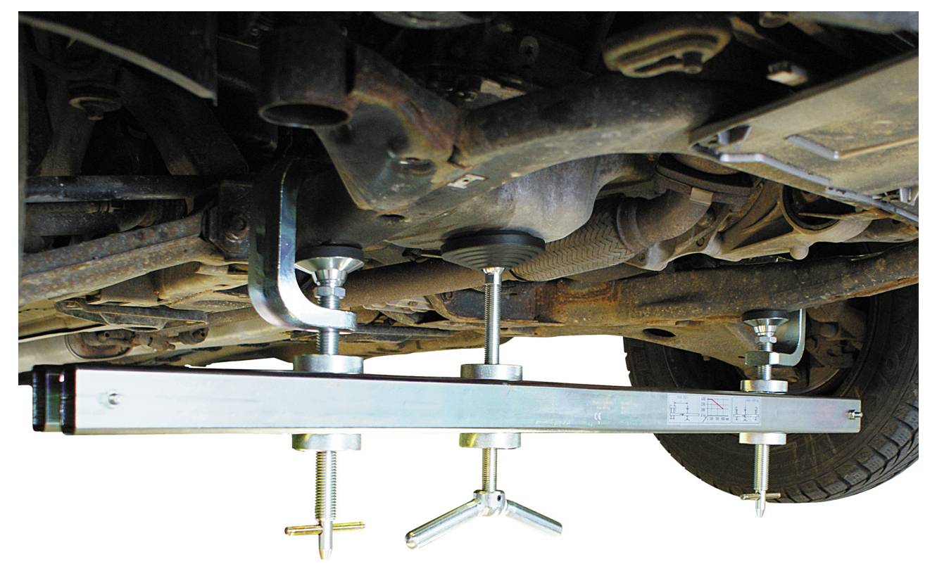 „Getriebe unter dem Fahrzeug, gesichert durch einen Tragbalken mit verstellbaren Schraubenmechanismen für Wartungs- oder Reparaturarbeiten."