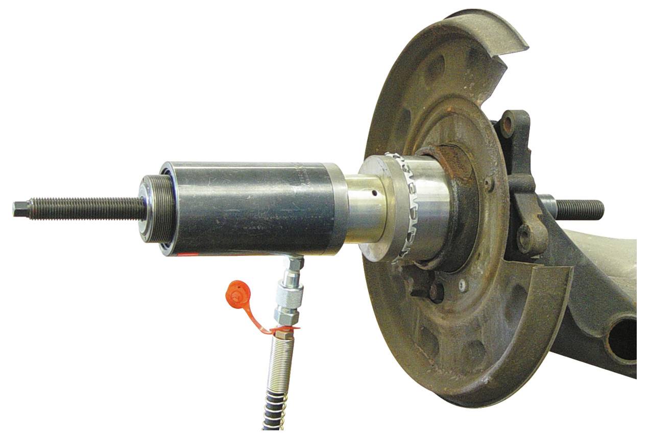 Ein Nahaufnahme eines Radnabenzieher-Werkzeugs, das an einer Radnabenbaugruppe eines Fahrzeugs befestigt ist und dessen Anwendung in der Automobilreparatur zeigt.