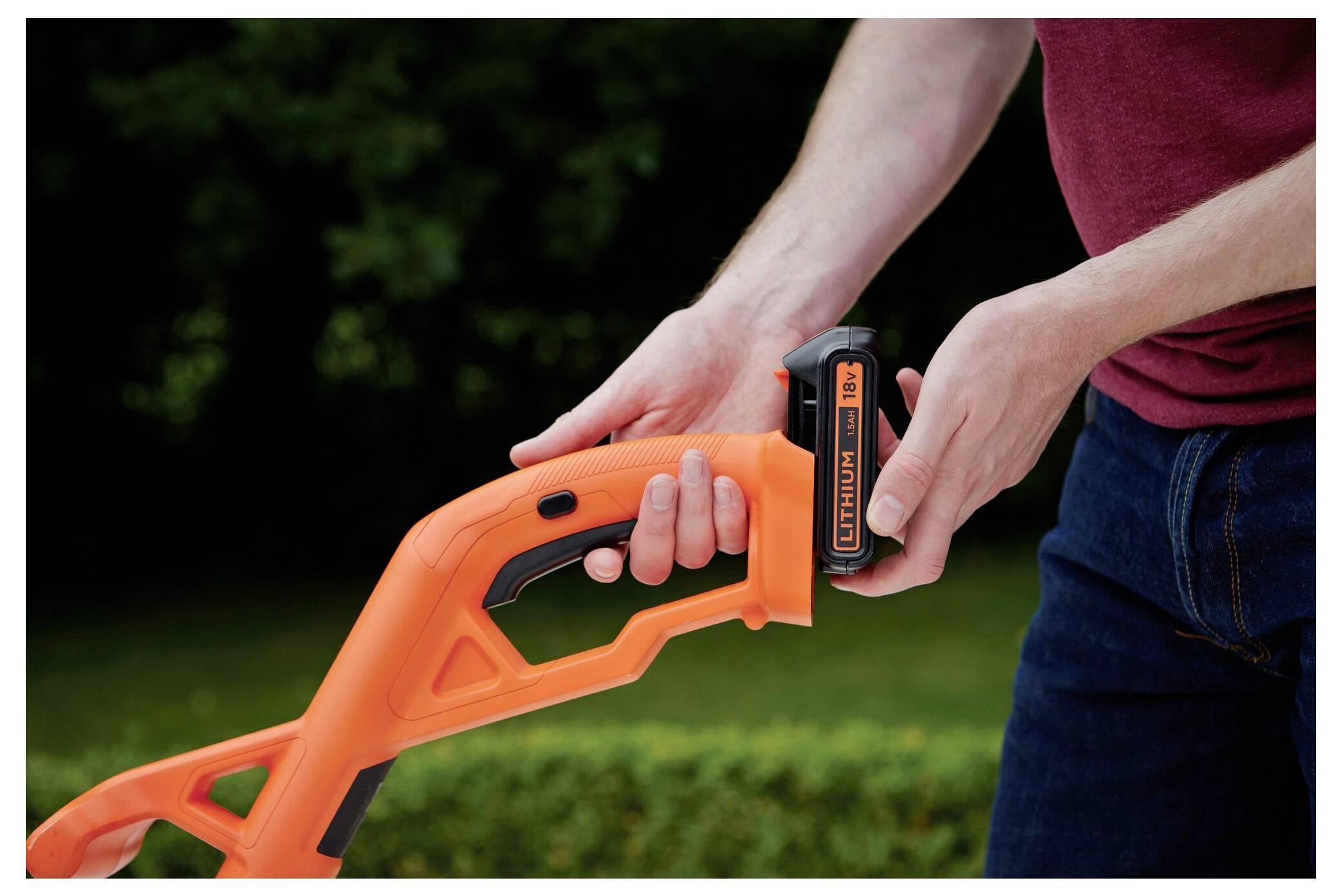 Ein Trimmer schneidet durch hohes grünes Unkraut, mit dem sichtbaren Markennamen „Black & Decker" auf dem Werkzeug, umgeben von dichter Vegetation.