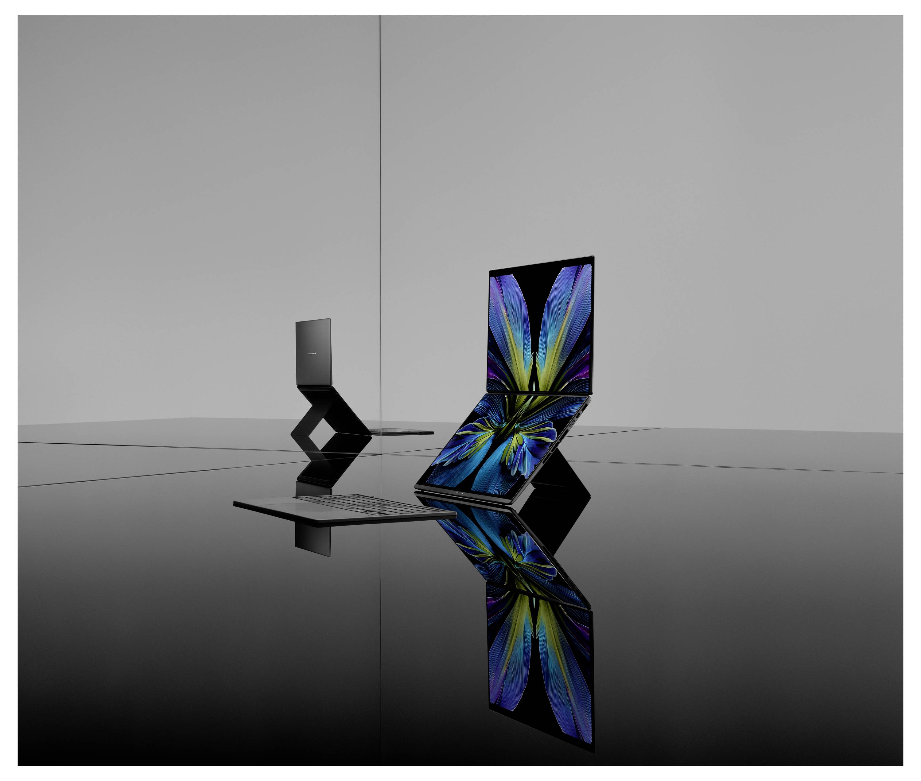 Zwei elegante Laptops mit flexiblen Scharnieren auf einer reflektierenden Oberfläche. Ein Laptop zeigt einen lebendigen Bildschirm, während der andere geschlossen und zusammengeklappt ist.