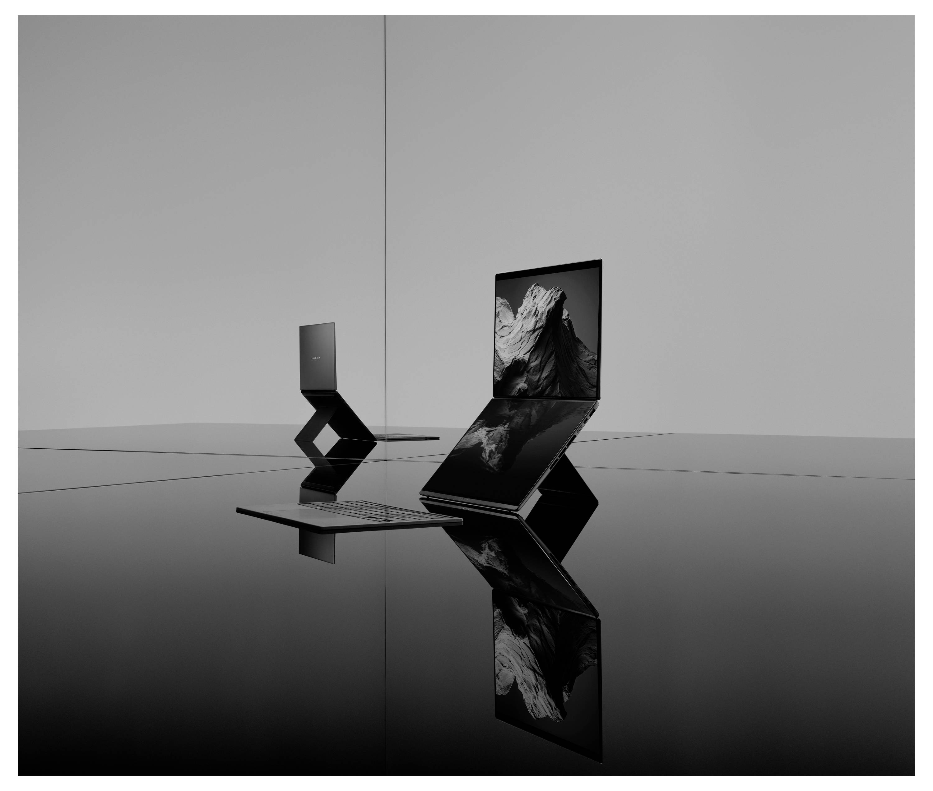 Zwei elegante faltbare Laptops auf einer reflektierenden schwarzen Oberfläche, einer offen in Zickzack-Form mit einem Bildschirm, der ein monochromes Blumenbild zeigt.
