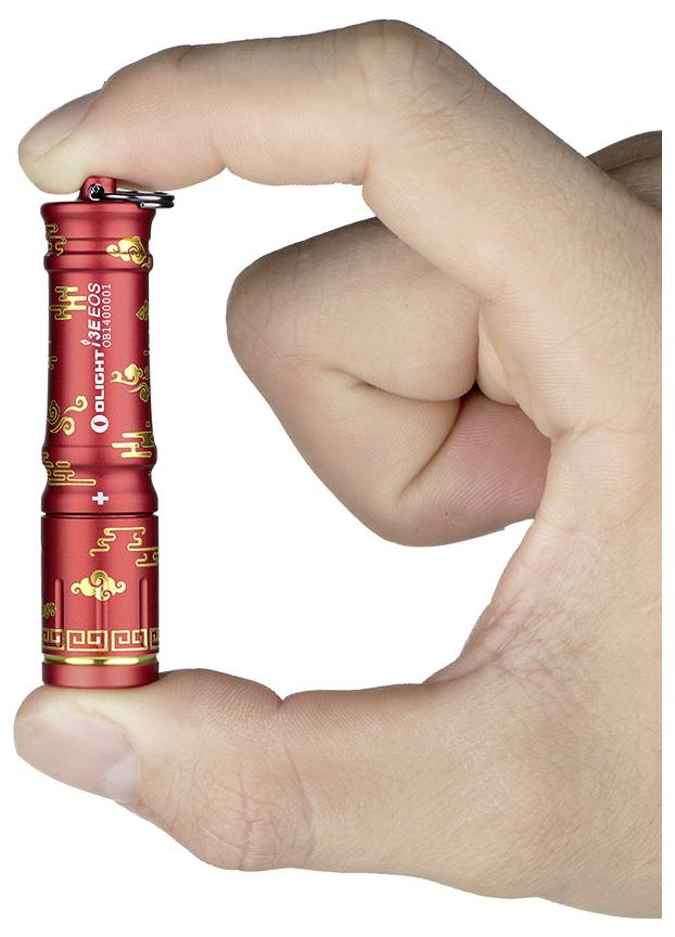 Eine Hand hält eine kleine rote Taschenlampe mit goldenem Dekorationsmuster und dem Markennamen 'Olight' darauf.