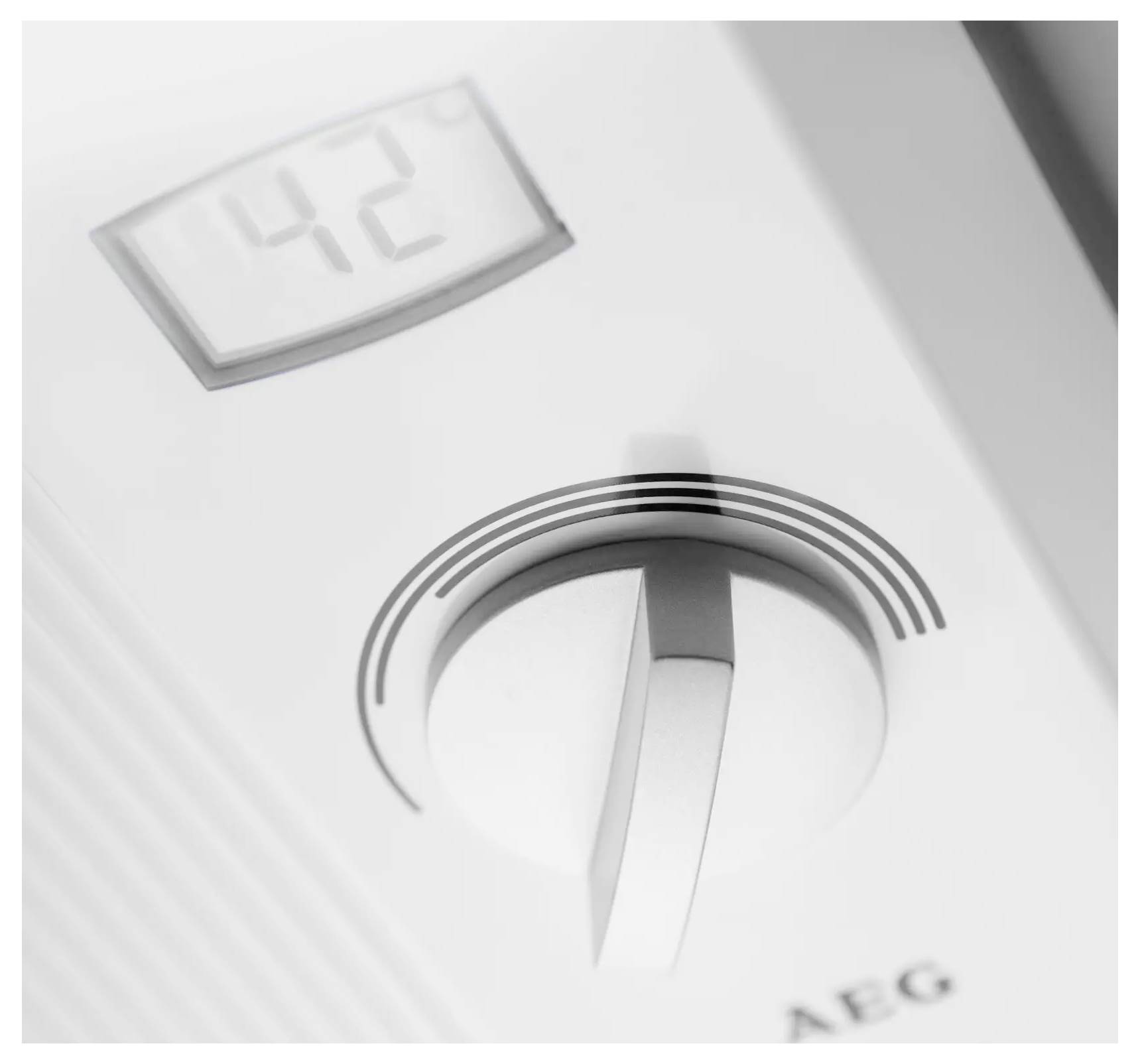 Eine Nahaufnahme eines weißen Thermostats auf 42 Grad eingestellt, mit einem analogen Zifferblatt und einer vertikalen Einstelllinie.
